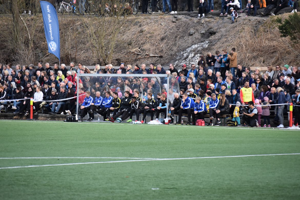 Starts benk, noen under tak og andre i friluft, følger nøye med.