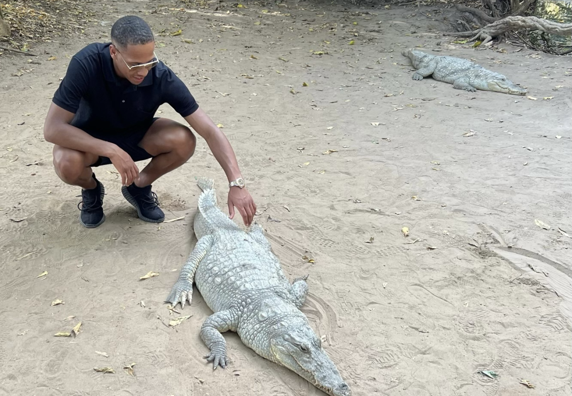 Bakau har litt over 40.000 innbyggere, og legenden sier at byen vokste opp rundt det hellige krokodillebassenget i Kachikally. Her klapper Zakaria en av krokodillene der. (Foto: Privat)