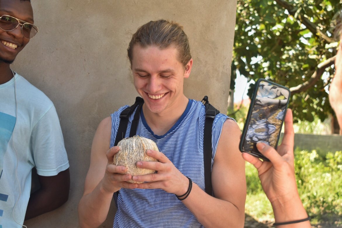 Mikael får smake en kokosnøtt, nyplukket fra et tre utenfor huset til en familie han fikk besøke.